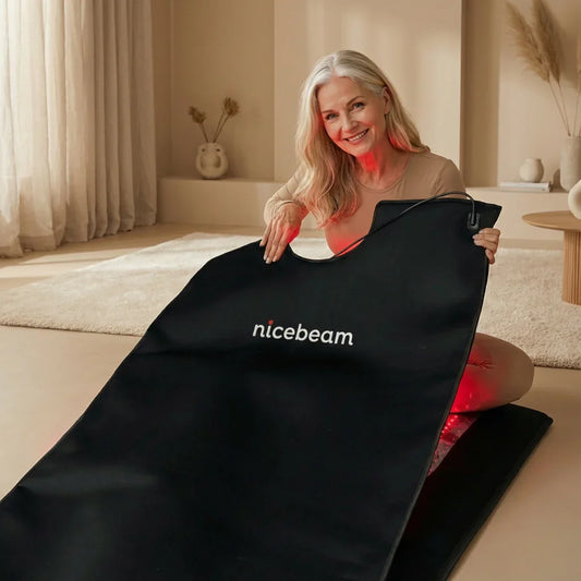 Older woman using Nicebeam red light therapy mat in a cozy home wellness setting