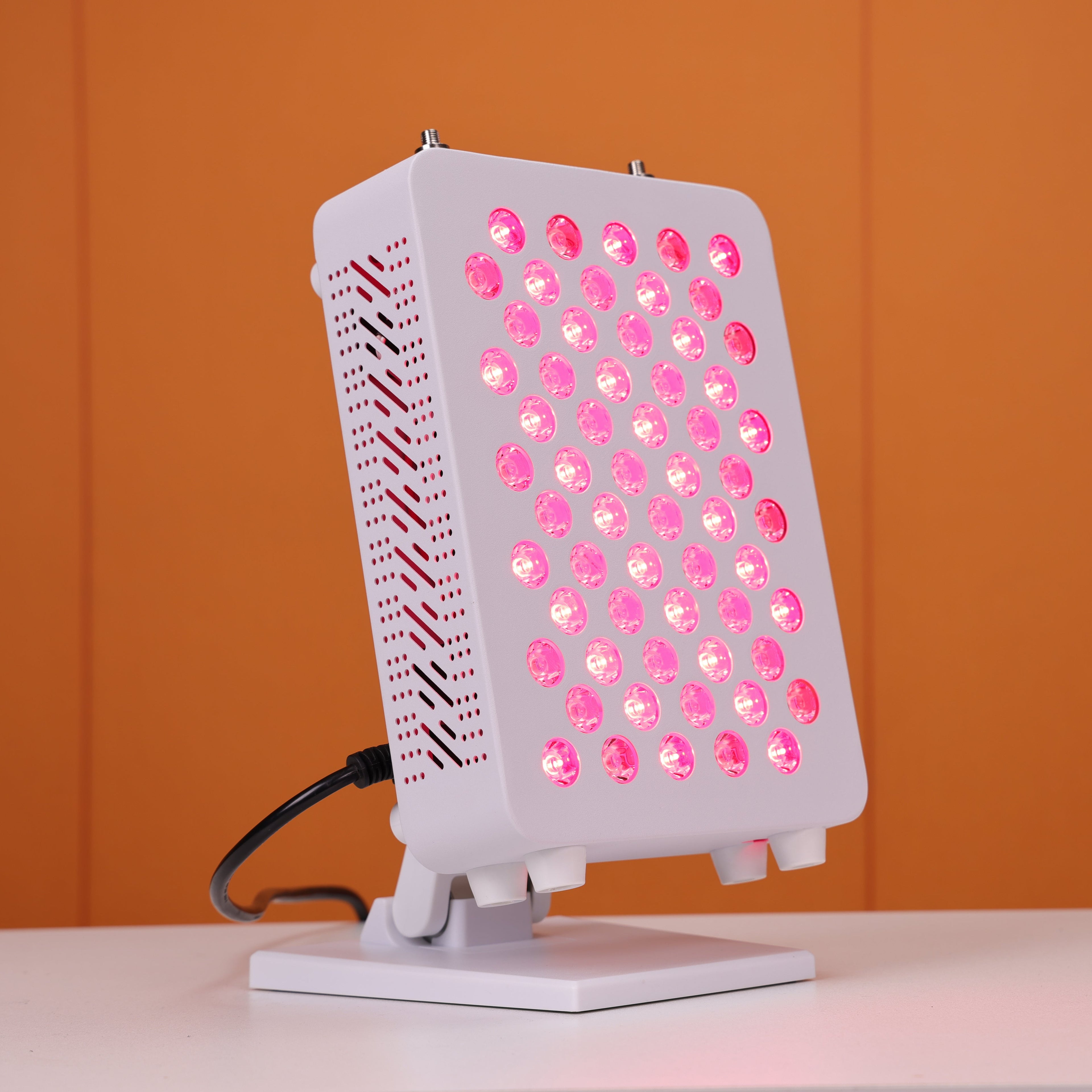 Nicebeam Red light therapy panel with a modern, compact design, featuring 60 LED lights emitting a therapeutic red glow, mounted on an adjustable stand, and placed against a vibrant orange background.