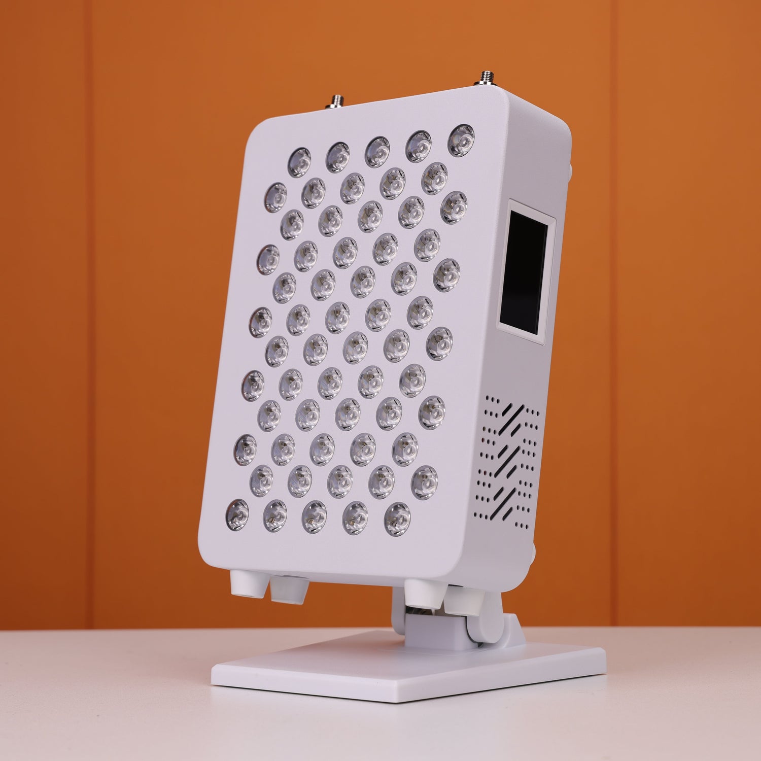 Angled view of a Nicebeam red light therapy panel featuring 60 unlit LED lenses, a touch-screen interface on the side, and a vented design for efficient heat dissipation, mounted on an adjustable stand and set against a vibrant orange background.