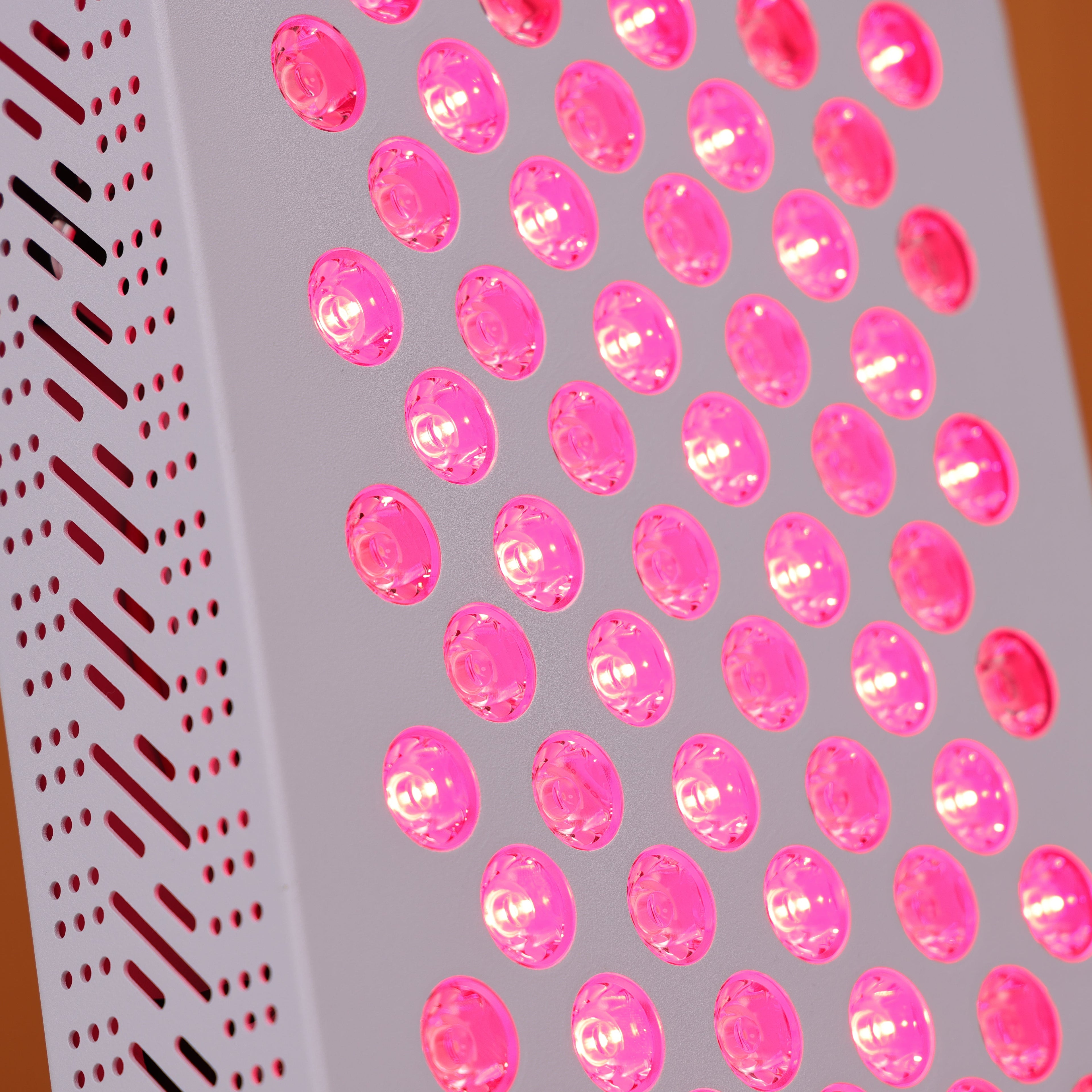 Close-up view of the Nicebeam red light therapy panel showcasing its 60 LED lights glowing brightly with a therapeutic red hue, alongside a vented side panel for efficient heat dissipation, emphasizing its sleek and functional design