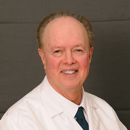 Male dermatologist in a white coat with a neutral expression