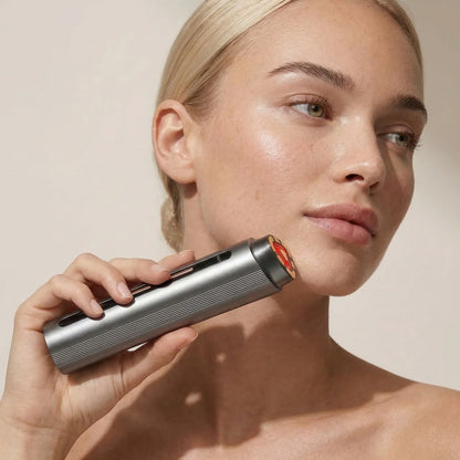 Woman using a handheld red light therapy device on her face for skincare wellness