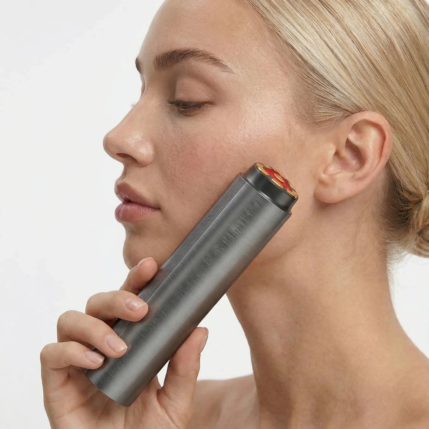 Woman using a handheld red light therapy device on her face for skin wellness