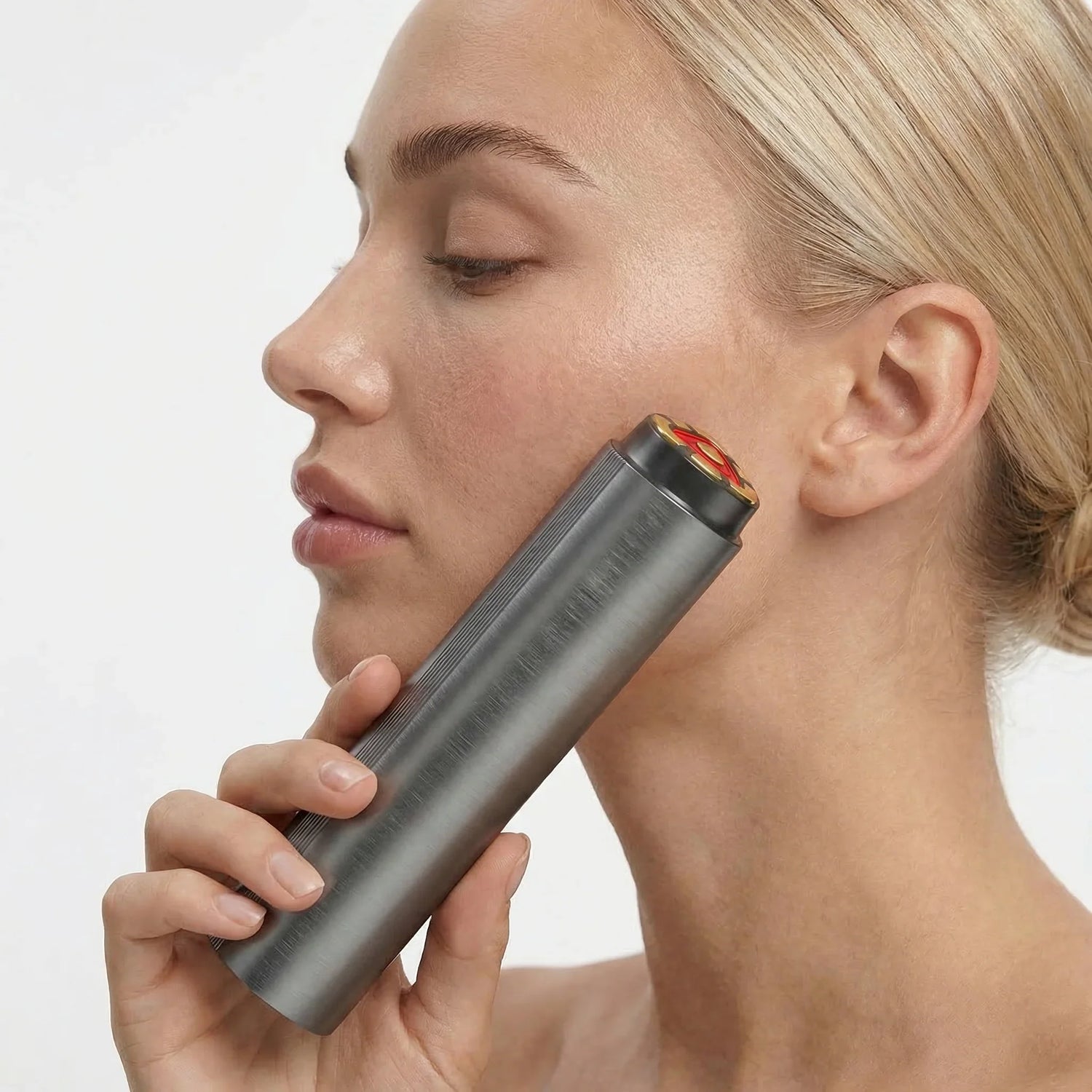 Woman using a handheld red light therapy device on her face for skin wellness