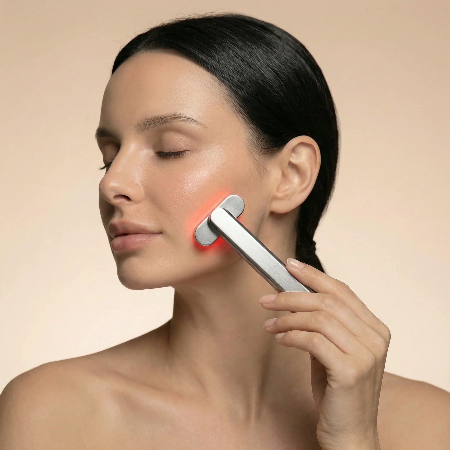 Woman using red light therapy device on face for skin rejuvenation and wellness