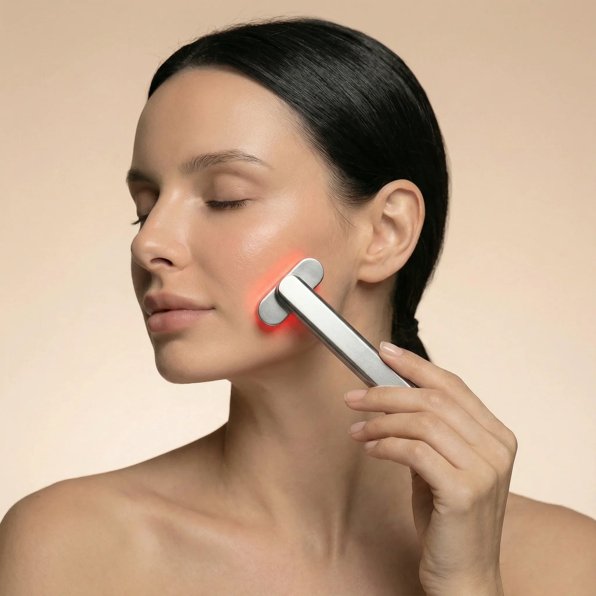 Woman using red light therapy device on face for skin rejuvenation and wellness