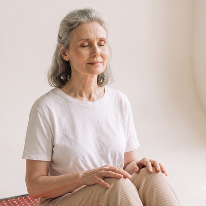 Woman sitting up on the Nicebeam red light therapy mat with eyes closed