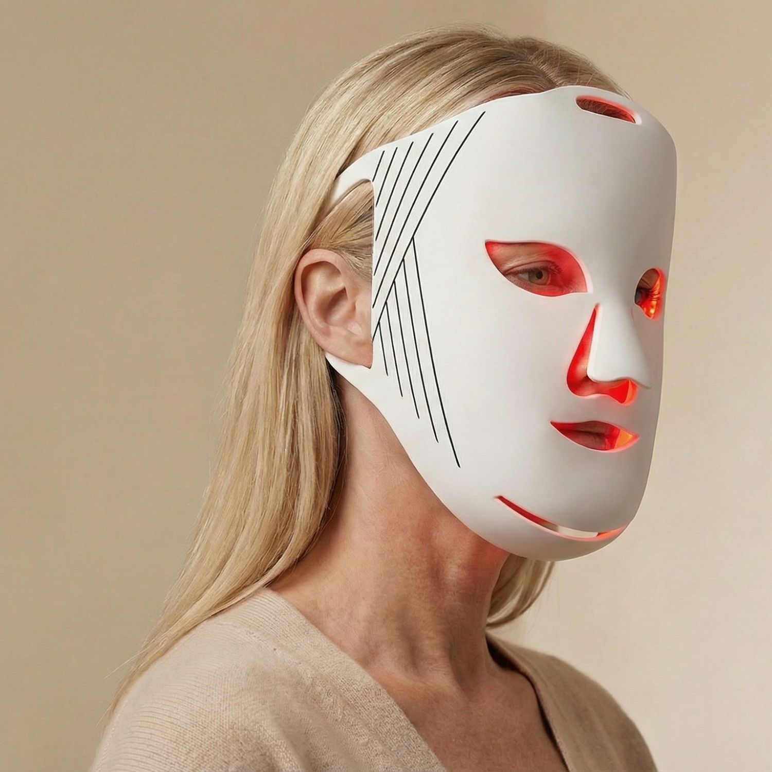 Person wearing a white LED face mask with red lights on a beige background