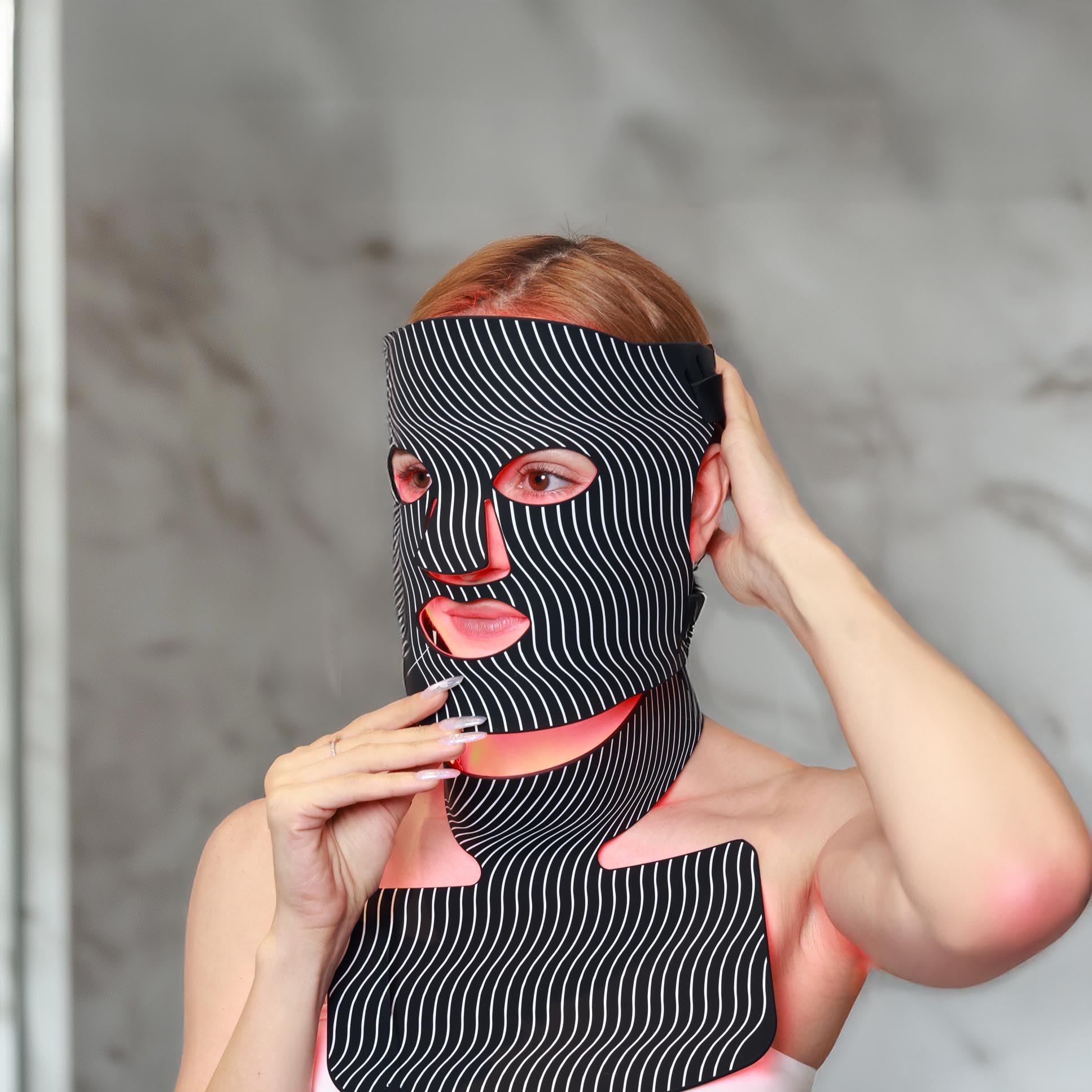 Woman wearing a Red Light Therapy Mask designed for face and neck rejuvenation, promoting skin health, anti-aging, and improved collagen production.