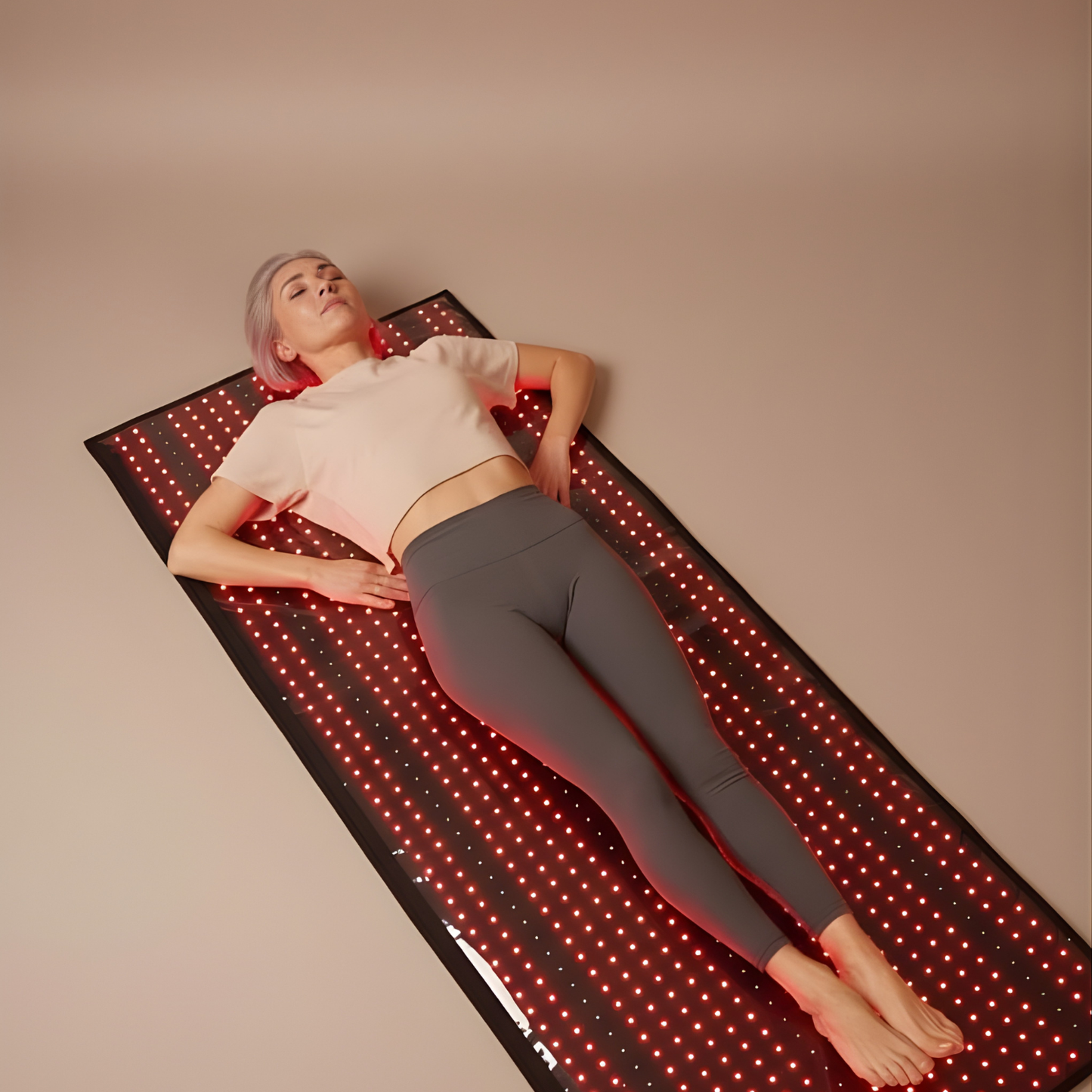 Person lying on a LED mat with a neutral background